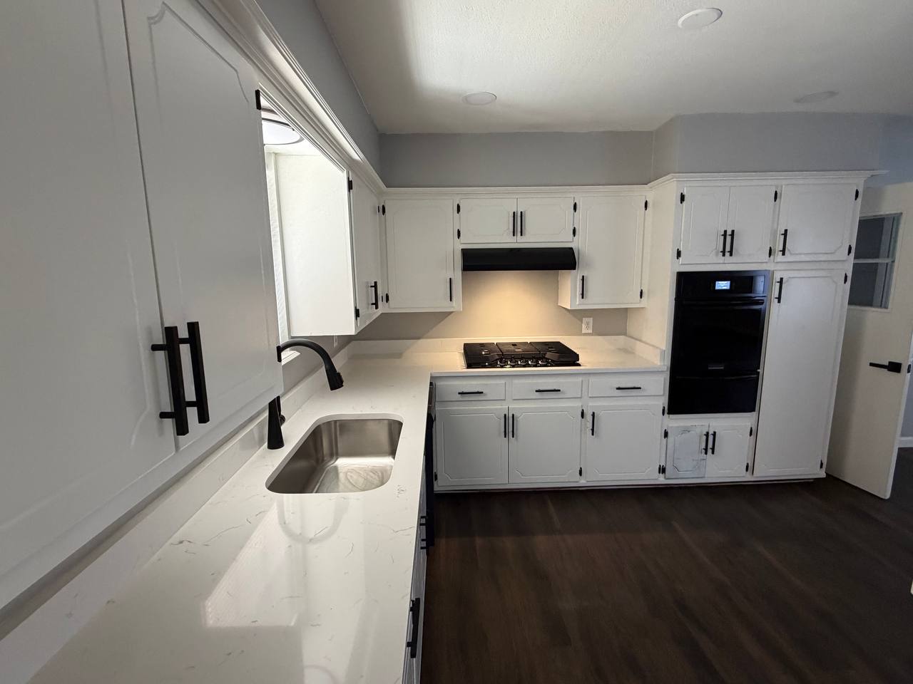 After — new undermount sink, black fixtures, and gas cooktop