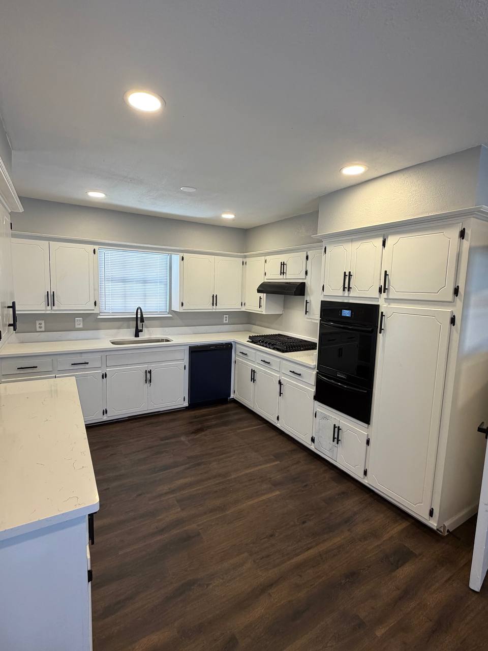 After — white refinished cabinets, quartz counters, and recessed lighting