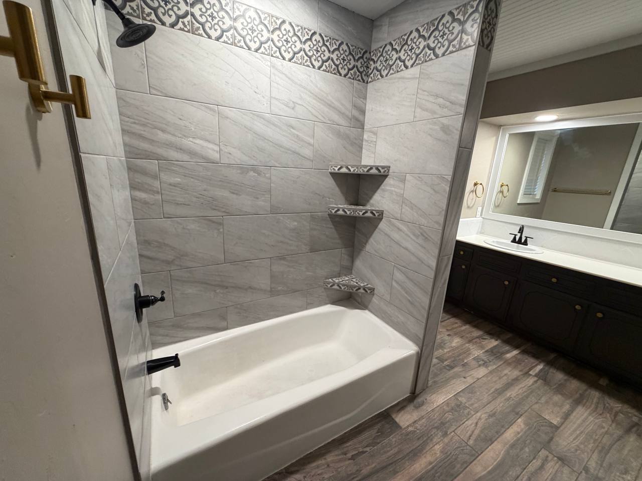 Tile tub surround with patterned border and built-in corner shelves