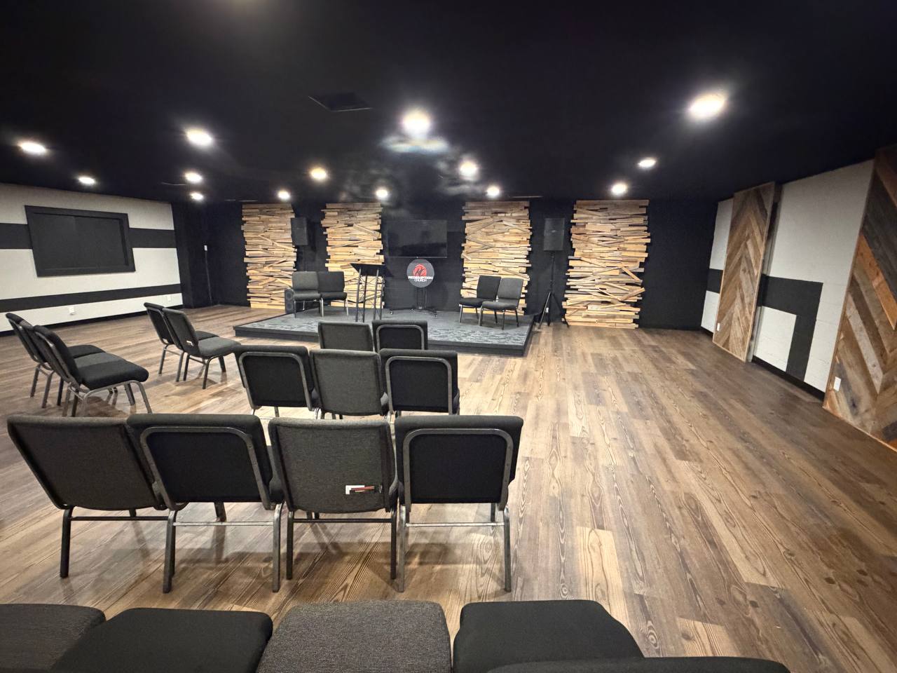 After — finished auditorium with reclaimed-wood stage backdrop